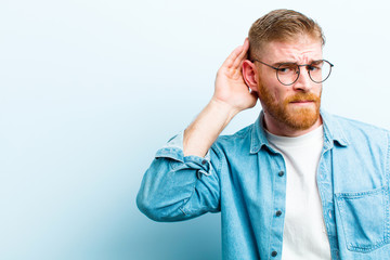 young red head man looking serious and curious, listening, trying to hear a secret conversation or...