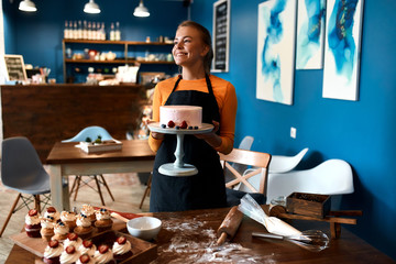 smiling cheerful girl holding yummy cake, looking aside, going to treat guests at home,close up photo. treatment