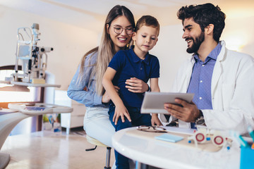 Portrait of optician with customers smiling in store.