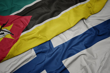 waving colorful flag of finland and national flag of mozambique.
