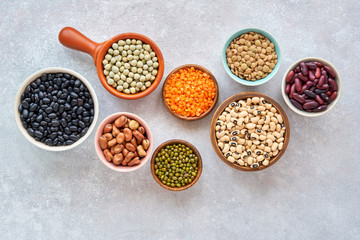 Obraz na płótnie Canvas Legumes and beans assortment in different bowls on light stone background . Top view. Healthy vegan protein food.