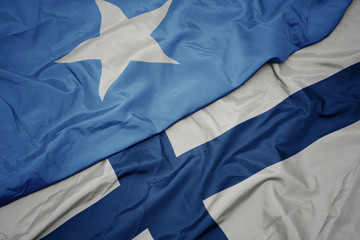 waving colorful flag of finland and national flag of somalia.