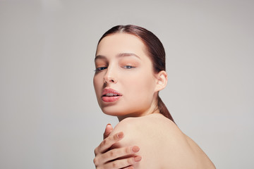 sophisticated girl with full lips, dark brown hair and radiant clean skin hugged herself on the...