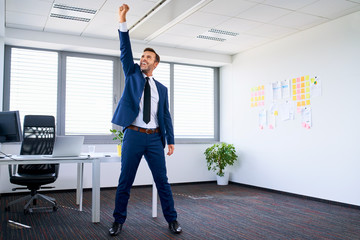 Successful businessman celebrating in office