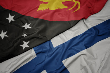 waving colorful flag of finland and national flag of Papua New Guinea .