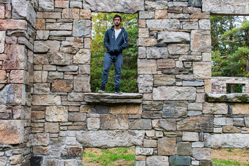 young man outdoors standing in window of abandoned building