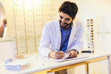 Confident optometrist, optician standing in store.