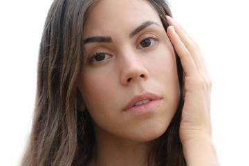 Portrait of a beautiful young girl with hand gently touching her forehead, looking into the camera