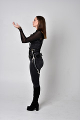 full length portrait of a pretty brunette woman wearing black leather fantasy costume. Standing...