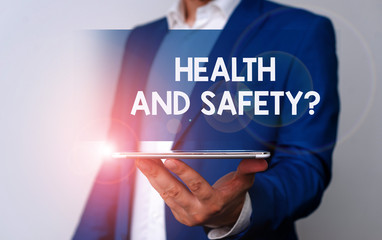 Handwriting text Health And Safety Question. Conceptual photo regulations and procedures to prevent accident or injury Man in the blue suite and white shirt holds mobile phone in the hand