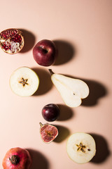 Five different kind of fruits on pastel background. Figs, plum, apple, pear and pomegranate. Top view shot, abstract food conception.