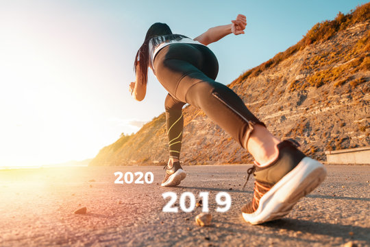 New year 2020 concept. Sports and Jogging along the sea. The woman stands ready to run. In the background, mountains and a narrow strip of sea. Bottom view