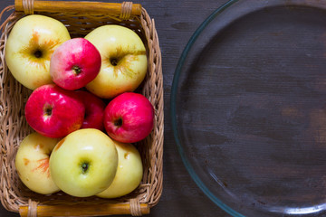 Apples and empty glass dish for baking on wooden background