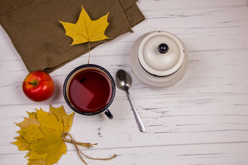 tea in a white cup with white sugar in cubes and cane sugar, maple leaves and apples on a wooden...