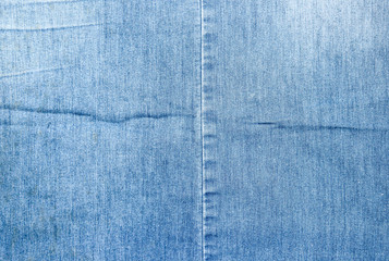 Texture of a blue denim fabric. Two pieces of fabric stitched together