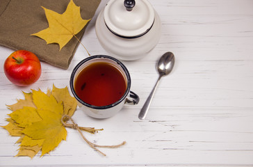 tea in a white cup with white sugar in cubes and cane sugar, maple leaves and apples on a wooden...