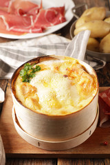 mont d'or, traditional french dish- cheese fondue with bacon, salami and potato