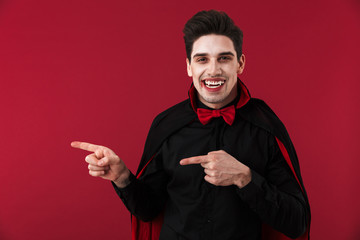 Image of vampire man with blood and fangs in black halloween costume