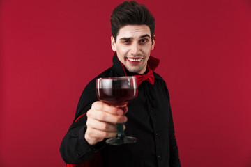 Image of vampire man with fangs in halloween costume drinking blood