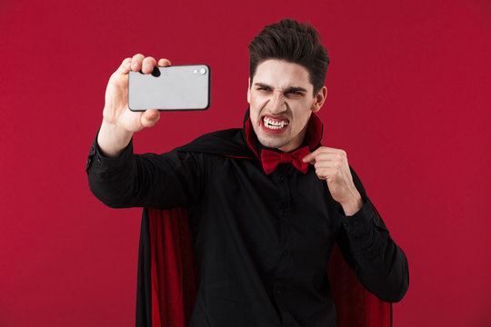 Image of vampire man in black halloween costume taking selfie photo
