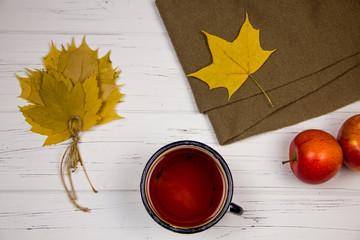 tea in a white cup with white sugar in cubes and cane sugar, maple leaves and apples on a wooden...