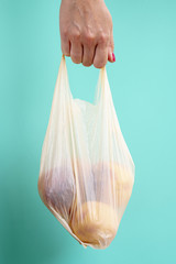 Person holding plastic bag with fruits