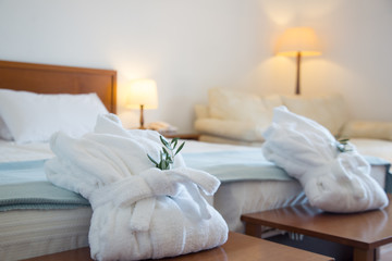Two folded bathrobes on bed in room	