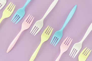 Top view colorful plastic fork on purple background