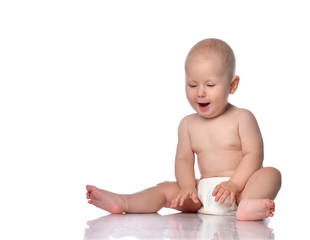 Happy infant child baby boy toddler in diaper is sitting  looking at something on the floor in...