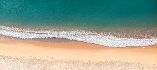 Aerial top view on the sandy beach. Umbrellas, sand, bridge and sea waves landscape.