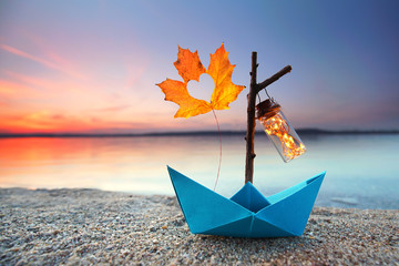 Papierboot mit Herbstblatt und Laterne