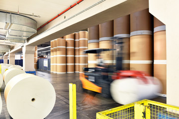 Warenlager mit Papierrollen und Gabelstapler in einer Großdruckerei // Warehouse with paper rolls...
