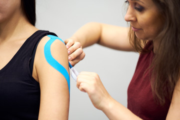 kinesiology taping treatment with blue tape on female patient injured arm. Sports injury kinesio treatment - obrazy, fototapety, plakaty