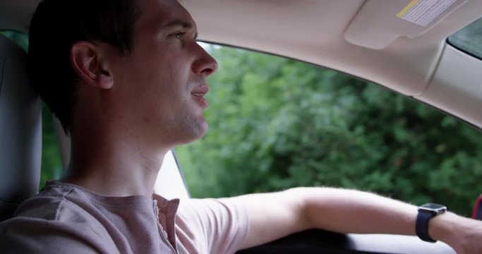 Young man driving electric car - close up on face in drivers seat