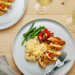 Delicious meal made of chicken fillet, green beans, mashed potato and vegetable sauce with white wine on a wooden table. Top view, above shot.