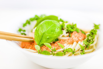 Italian pasta with chopsticks, tomato sauce, parmesan cheese, fresh oregano and basil - on white background.