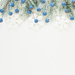 Christmas card composition. Xmas border with blue frozen berries, snowflakes and Xmas tree branch isolated on white background. Colorful Xmas decor