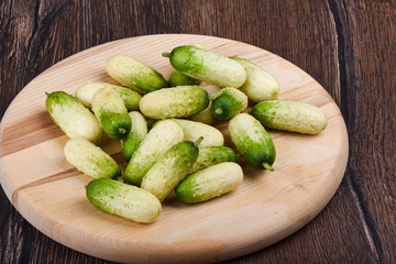 Fresh ripe little cucumbers on a wooden cutting board.