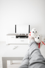 Woman looking at TV with legs on the table in living room.