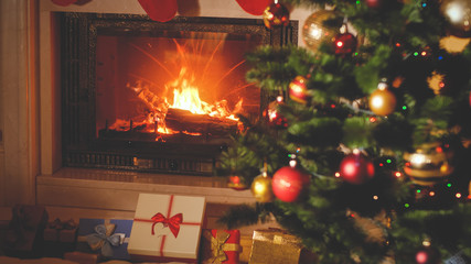 Toned Christmas background with Christmas gifts and presents boxes under Xmas tree and burning...