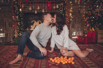 Lovely couple in christmas interior in studio with mandarins.