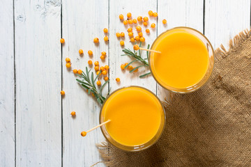  Two glasses of healthy vitamin sea buckthorn smoothie on a white wooden background. Top view.
