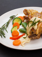 Rabbit legs baked in white wine with bechamel sauce on a ceramic plate.