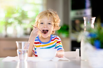 Child eating breakfast. Kid with milk and cereal.