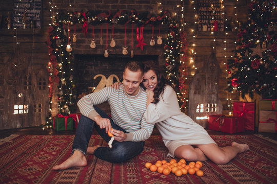 Lovely prettyy couple in christmas interior at home with mandarins.