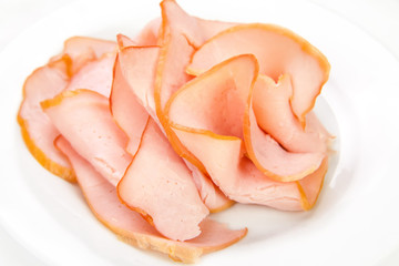 Sliced meat pieces, bacon, cold boiled pork, balyk on a white plate. Isolated on white background. Snack. Meat dish. Closeup