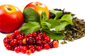 Composition. Black and green tea leaves, apples, berries, fresh mint, on a white plate. Isolated on white background