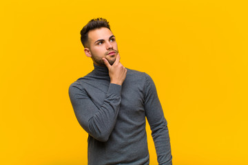young hispanic man thinking, feeling doubtful and confused, with different options, wondering which...
