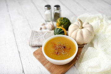 Pumpkin vegetable soup on white wooden backdrop and seasonings. Fall harvest soup 