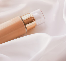 Tonal bb cream bottle make-up fluid foundation base for nude skin color on silk background,...